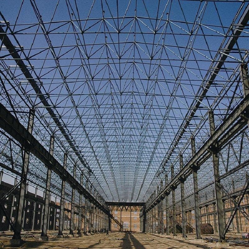 Long-span steel roof trusses seen from below inside an industrial hall