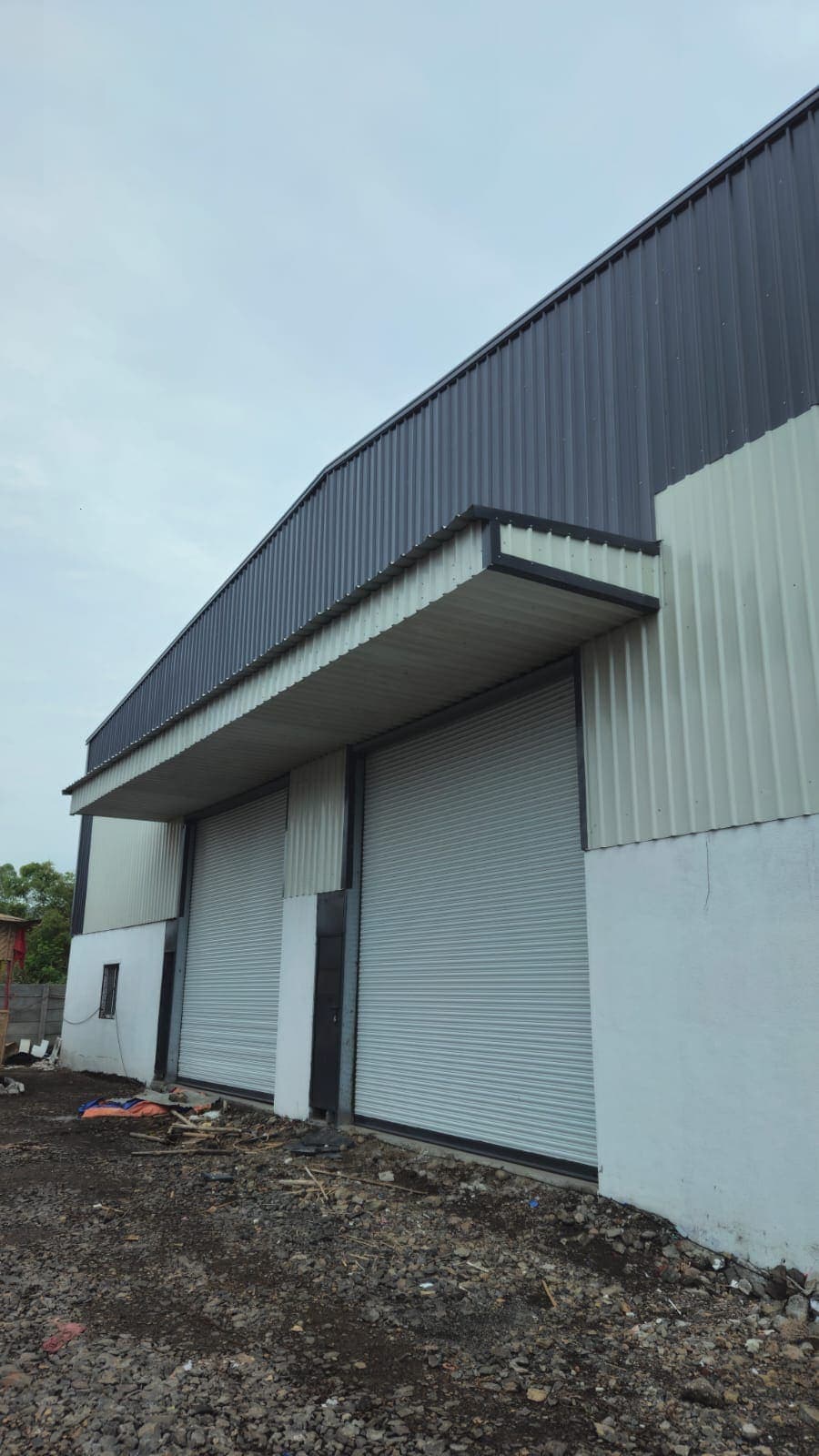 Clad end wall of the manufacturing unit with roller shutters