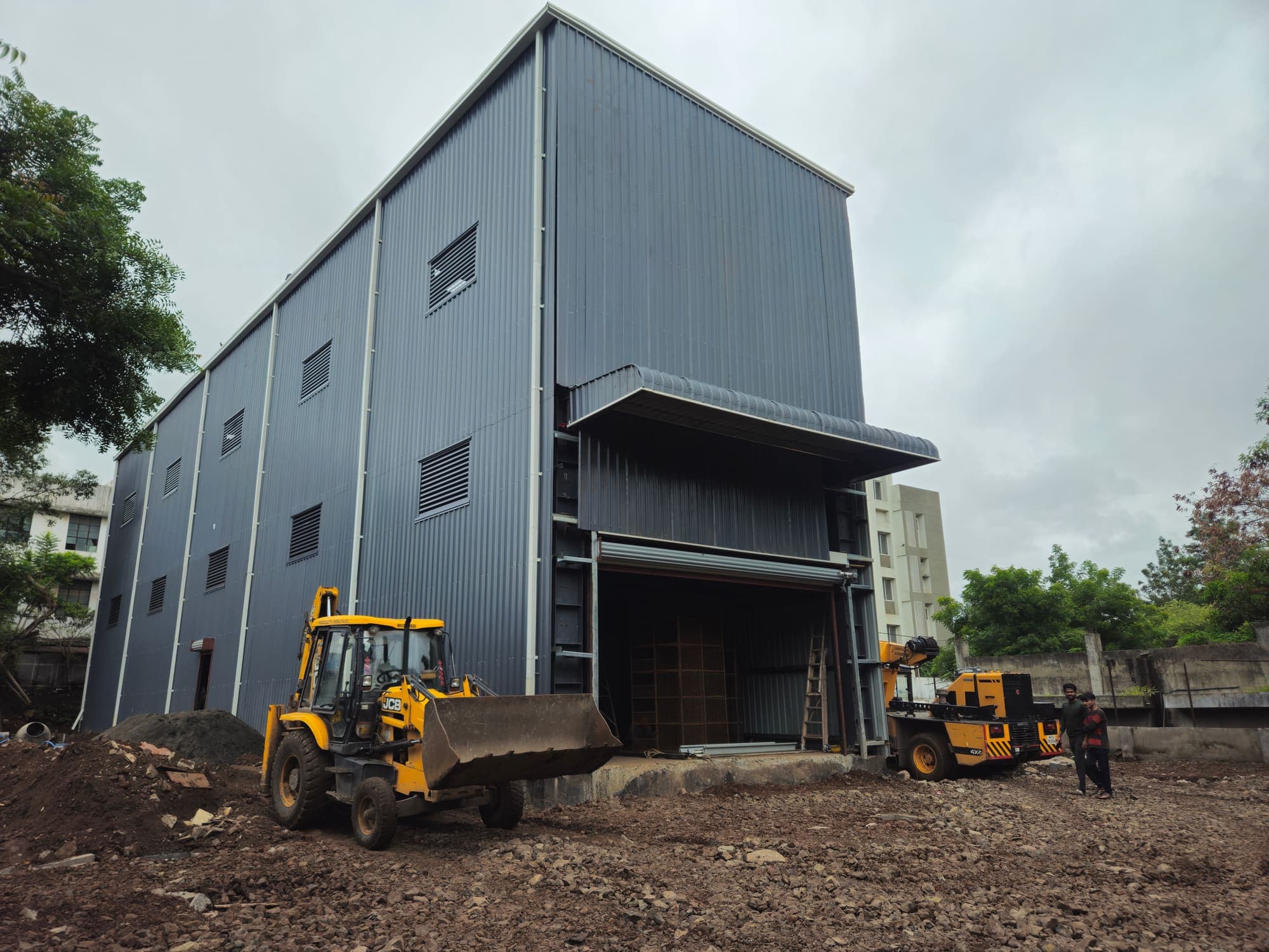 Completed G+4 steel stockyard building with dark grey cladding